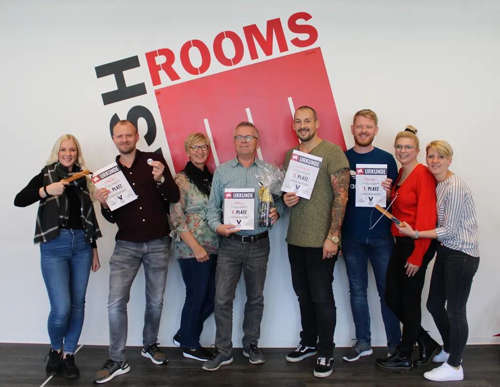 Acht Kolleginnen und Kollegen stehen mit Urkunden nebeneinander vor der BASH-ROOMS-Wand